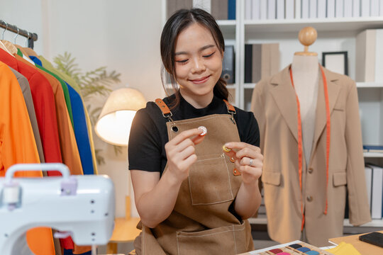 Professional fashion designer selecting fabric swatches, thread colors and sewing supplies in a modern studio. Creative textile design, apparel development and garment production.