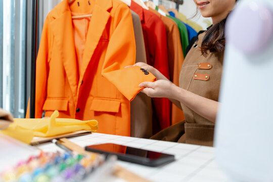 Professional fashion designer inspecting garment details, comparing fabric colors and checking clothing quality in a modern fashion studio. Creative apparel development and textile craftsmanship.