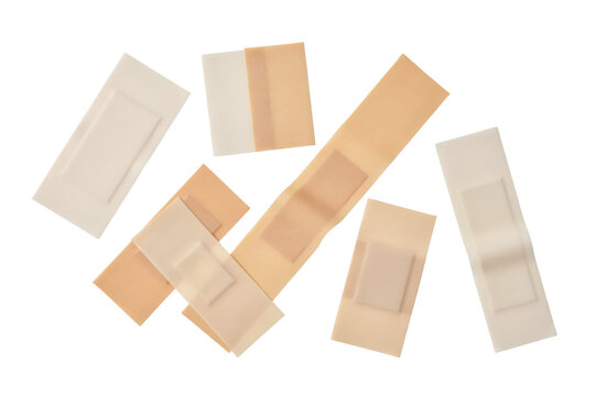 Assorted adhesive bandages and sterile medical strips in various sizes and beige tones arranged on white surface isolated on a transparent background