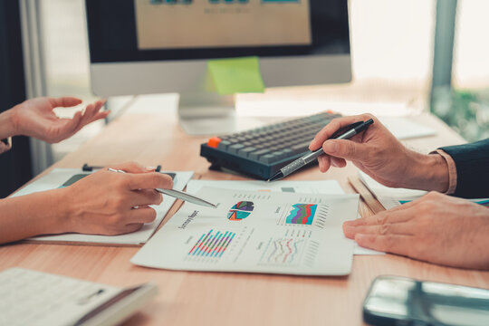 Business people working together discussing financial chart statistics and analysis strategy with laptop computer at office table.