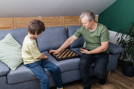 Father and son playing chess, learning strategy at home
