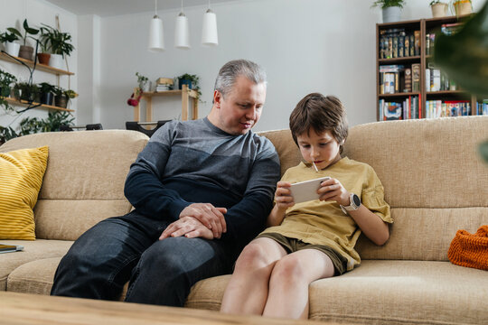 Father and son bonding playing mobile game at home
