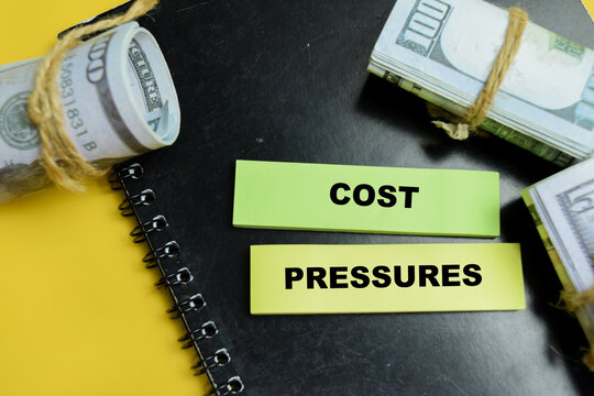 Concept of cost pressures write on sticky notes isolated on table. For financial inflation and budget stress