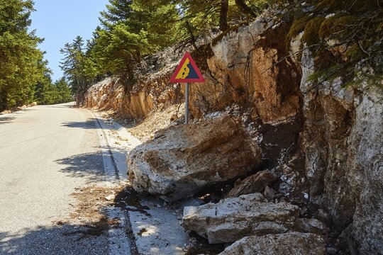 Triangular road sign Attention falling rocks huge boulder on the roadside, Enos mountain, Kefalonia island, Ionian Islands, Greece