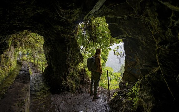 Hikers on a trail along a levada through a tunnel, Levada do Caldeir&atilde;o Verde, Parque Florestal das Queimadas, Madeira, Portugal