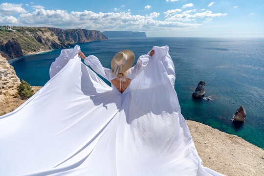 Woman dress ocean, a woman in a long white dress standing on a cliff edge overlooking a blue sea