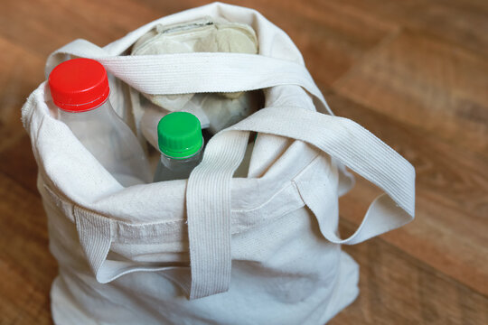 Reusable fabric shopping bag filled with bottles and household purchases is ready to carry home. Concept of eco conscious shopping, reducing disposable bags and caring for nature.