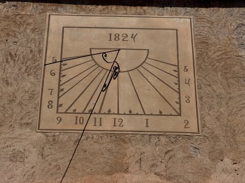 Antique sundial displaying 1824 year on a textured building wall, marking time with a gnomon shadow in manacor, balearic islands, spain