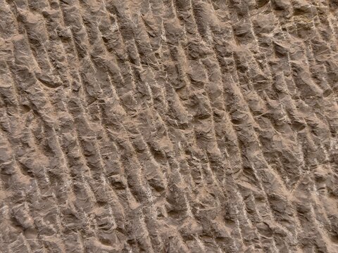 Rough stone wall texture creating a weathered background pattern, showing detailed diagonal chisel marks on a hard rock surface in manacor, balearic islands, spain