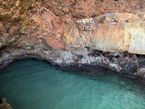Natural sea cave with vibrant turquoise water reflecting colorful rock formations, creating a tranquil hidden grotto in manacor, balearic islands, spain