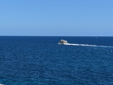 Passenger boat navigating the deep blue mediterranean sea under a clear sky, leaving a white wake, symbolizing travel, tourism, and summer vacation in balearic islands, spain