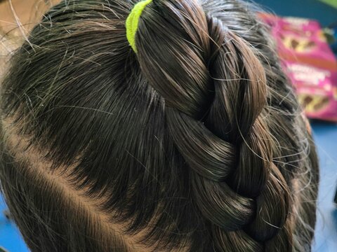 Close-up of high braided ponytail hairstyle with green hair tie on brunette hair