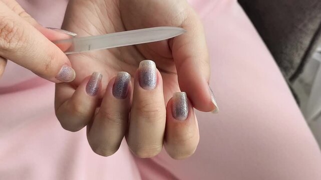 Close up of a woman shaping her fingernails with a manicure file, illustrating nail care, home beauty treatment, personal hygiene and self-care.