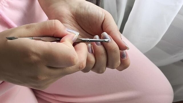 Woman carefully treating the cuticles around her fingernails at home, symbolizing manicure, hand care, nail hygiene, self-care and beauty routines.