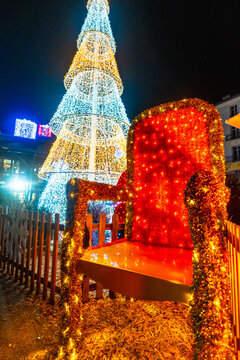 Large santa claus chair and illuminated christmas tree decorations