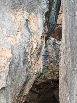 Narrow passage between giant natural limestone rock formations and cave entrance opening