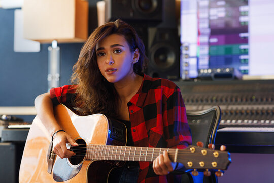 Young woman singing emotionally and playing one acoustic guitar