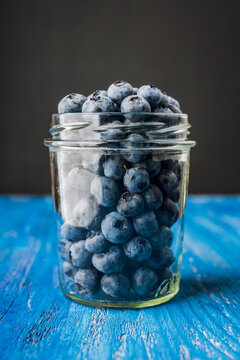 Glass jar with fresh blueberries on dark rustic background. Selective focus.