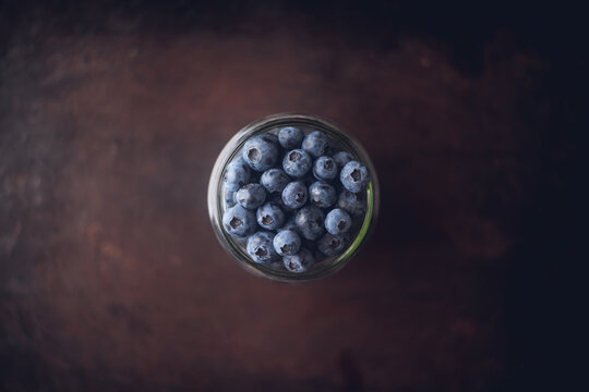 Glass jar with fresh blueberries on dark rustic background. Shot from above.