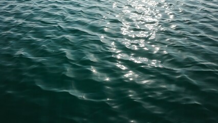 Fototapeta premium Dark blue ocean water surface with gentle ripples and bright sunlight reflections sparkling on the moving waves