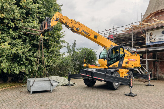 Construction site infrastructure and heavy machinery, telescopic handler lifting a metal container at a building renovation project in Lintig, Germany