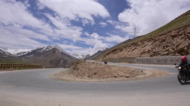 Ladakh, India : Slow motion footage of motorcycle rides on curvy mountain road in Khardung La pass, famous mountain pass near Leh of Ladakh, India with mountains in the background on sunny day