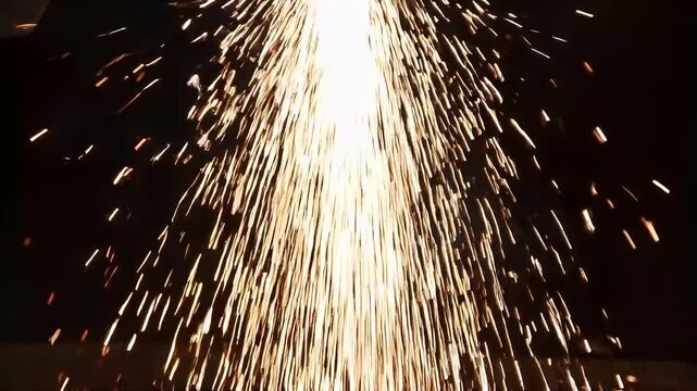 Brilliant glowing sparks flying in a dark workshop environment during metal cutting work