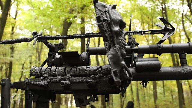 Post-apocalyptic theme, battle-ready, dystopian setting. Spiked, battle-ready metal framework stands within forest, giving off rugged, end-of-world vibe.