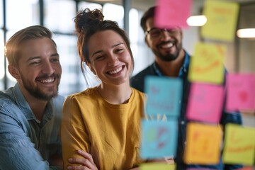Obraz premium Professional diverse startup team brainstorming around a transparent glass board filled with colorful business strategy notes