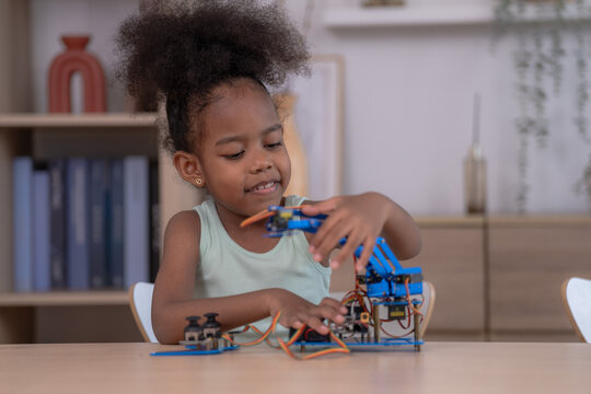 A creative little student tinkers with a blue robot arm at the table in a cozy home study corner, discovering technology through play in a warm welcoming home ideal for parenting and.