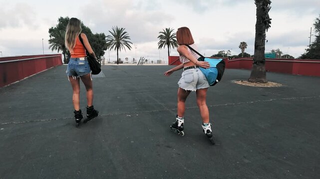 Young women rollerblading together outdoors on a promenade