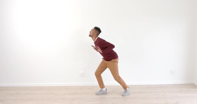 Young man practicing dance moves in empty room, focusing on balance