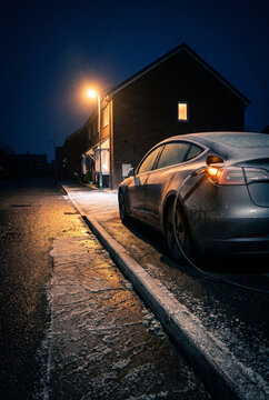 Night EV Charging on a Residential Street with Curbside Sedan