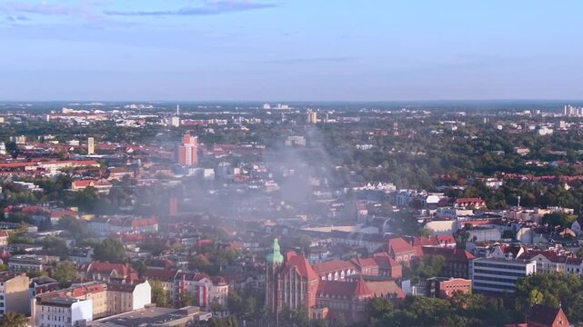 Smoke column rising over Berlin buildings, indicating a significant fire incident and potential infrastructure impact. Wonderful aerial view ascending drone panorama