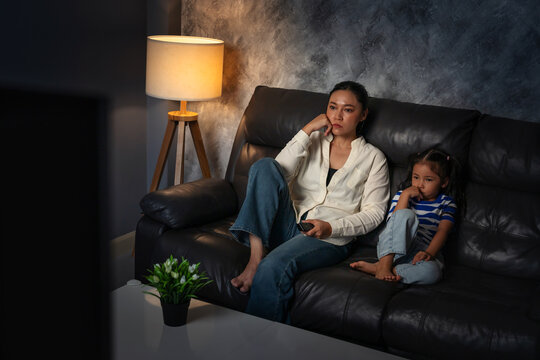 bored mother and daughter watching tv in the living room at night
