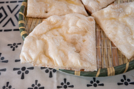 Fresh baked Indian naan flatbread slices served on a woven plate.