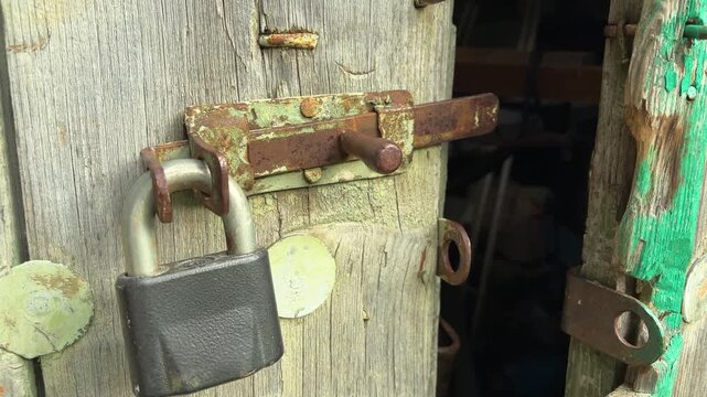 Rusty latch and padlock on an old wooden barn door