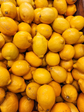 Yellow lemons filling the frame, creating a vibrant background texture representing fresh produce, healthy eating habits, citrus fruit, and vitamin c. Vertical photo