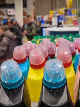 Rows of various branded cleaning product bottles, including detergent and disinfectant, standing on a shelf inside a grocery store, providing household chemical options for shoppers. Vertical photo