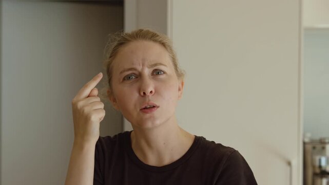 Confused woman pointing at her head with a puzzled facial expression, showing uncertainty, misunderstanding and questioning.