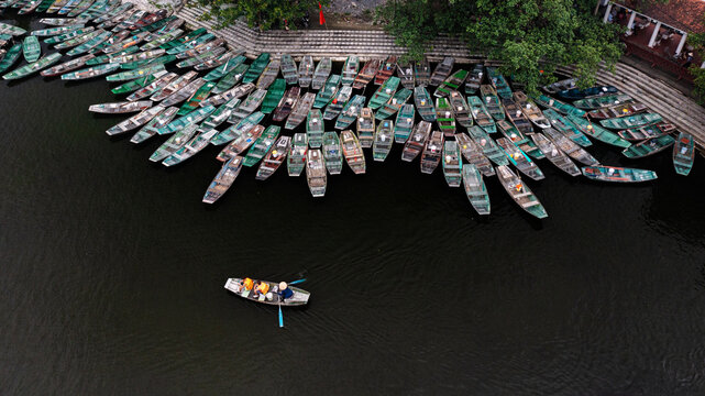Colorful Boats on a Dark River. Aerial view of numerous traditional boats gathered on a dark river, creating an abstract pattern and striking texture on the water.
