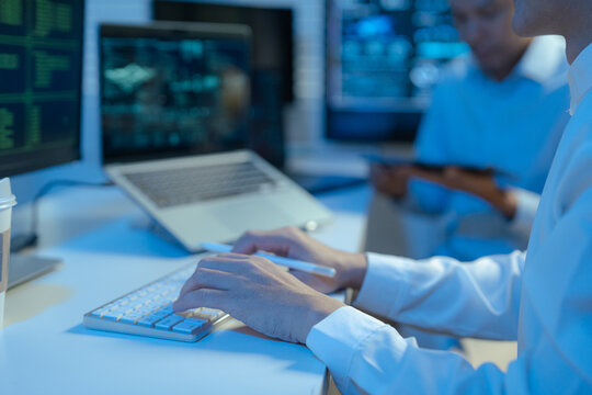 Male coder or developer working overtime using a computer display in problem solving at workplace.
