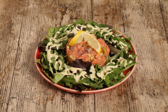 Pr&eacute;paration d'un tartare de saumon sur un lit de salade verte
