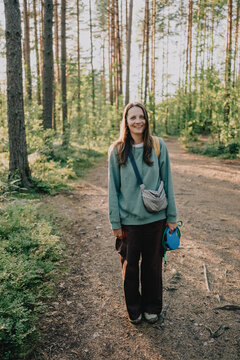 Smiling woman holding dog leashes on a forest trail during an outdoor walk, representing active pet ownership, daily dog care, recreation and pet-friendly lifestyle.