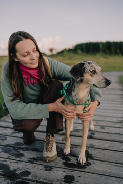Woman gently embracing her dog on a wooden boardwalk outdoors, showing a caring human-animal relationship, pet companionship, trust and responsible ownership.
