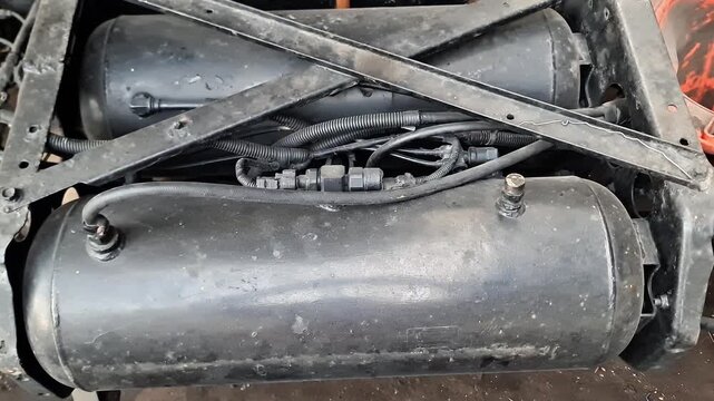 Industrial heavy truck chassis undercarriage featuring dual air brake pressure tanks and steel framework