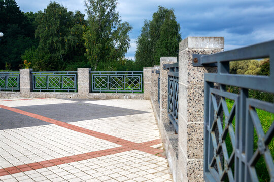 Ornate forged iron railing panels set into granite stone pillars line paved urban overpass viewpoint with copy space