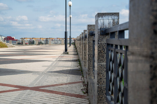 Linear perspective of granite fence posts along patterned paved pedestrian overpass square on sunny day with copy space