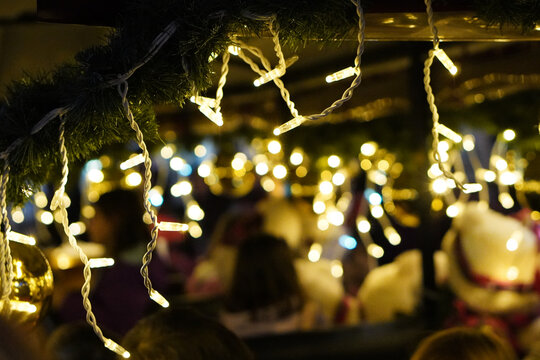 Horizontal image with a dark background, Christmas lights and a crowd at a Christmas market