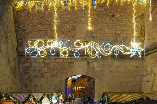 lighting and a Christmas market decorating a section of a stone wall or a historic archway